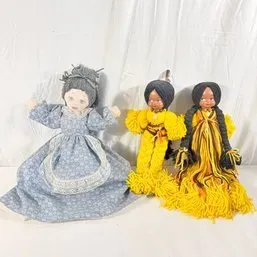 Sale Photo Thumbnail #74: Trio of handmade vintage dolls, including one in a blue patterned dress with an apron and two yarn-dressed figures in yellow and orange attire.