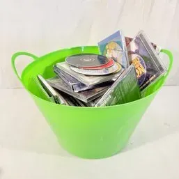 Sale Photo Thumbnail #86: Bright green plastic flex tub filled with an assortment of music compact discs and DVDs in jewel cases.