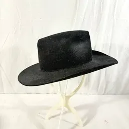Sale Photo Thumbnail #117: Black felt cowboy hat with a wide brim, displayed on a plastic stand.
