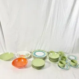 Sale Photo Thumbnail #49: Vintage mid-century Melmac plastic dinnerware set in avocado green, orange, and patterned white pieces, including plates, bowls, teacups, and saucers.