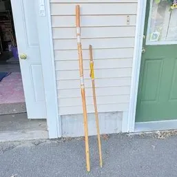 Sale Photo Thumbnail #44: Pair of wooden hiking sticks leaning against a vinyl-sided building exterior.