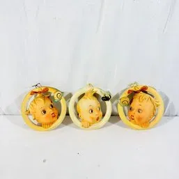 Sale Photo Thumbnail #124: Set of three vintage mid-century baby head ornaments inside plastic hoop frames, featuring painted facial expressions and hair bows.
