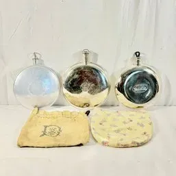 Sale Photo Thumbnail #113: Collection of three vintage silver-toned metal pocket flasks shown with two fabric storage pouches.