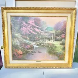 Sale Photo Thumbnail #258: Thomas Kinkade framed art print depicting a romantic garden landscape with a gazebo and stream, housed in an ornate gold-finished frame.