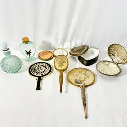 Sale Photo Thumbnail #139: Collection of vintage vanity accessories, including ornate hand mirrors, glass perfume bottles, compacts, and a clam shell jewelry dish.