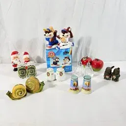 Sale Photo Thumbnail #128: Collection of novelty salt and pepper shakers in various designs, including snails, sports mascots, apples, and Santa figures.