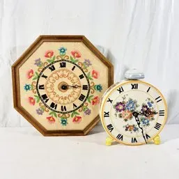 Sale Photo Thumbnail #150: Pair of vintage floral-themed clocks, including an octagonal wood-framed wall clock with hand-painted folk art details and a round porcelain alarm-style tabletop clock.