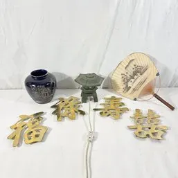 Sale Photo Thumbnail #230: Collection of Asian decor items including brass Chinese character wall plaques, a dark blue glazed vase with etched details, a miniature pagoda lantern lamp, and a wooden hand fan.