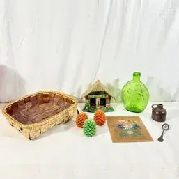 Sale Photo Thumbnail #170: Assortment of vintage home decor items, including a woven split-wood basket, a Swiss chalet music box, a green glass bottle, ceramic pinecone salt and pepper shakers, a small floral print, and a miniature stoneware jug.