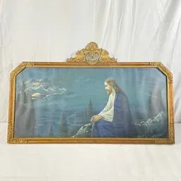 Sale Photo Thumbnail #131: Vintage framed religious print depicting Jesus in contemplation, housed in an ornate gilded wood frame with a crest detailing, early-to-mid 20th century.