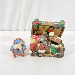 Sale Photo Thumbnail #189: Two resin cat figurines featuring a Siamese cat sleeping on a blue armchair alongside a Christmas-themed kitten playing inside an open luggage trunk.