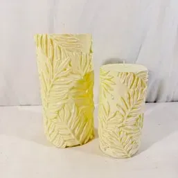 Sale Photo Thumbnail #52: Pair of cream-colored pillar candles featuring embossed palm leaf textured designs in two varying heights.