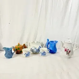Sale Photo Thumbnail #185: Collection of vintage ceramic teapots, creamers, and cups, featuring blue floral, floral transferware, and novelty bird-shaped designs.
