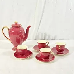 Sale Photo Thumbnail #75: Vintage dark pink porcelain tea set featuring a tall coffee or teapot with gold-gilt handle and trim, accompanied by four matching teacups and saucers.