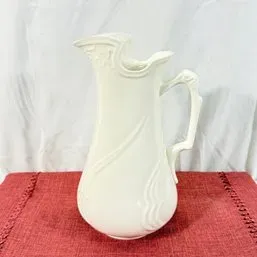 Sale Photo Thumbnail #142: Vintage white ceramic pitcher featuring molded swirl details and an ornate handle.