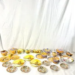 Sale Photo Thumbnail #62: Collection of vintage hand-painted Japanese porcelain teawares, featuring scenic landscapes and gilt trim on various saucers, teacups, teapots, and serving pieces.