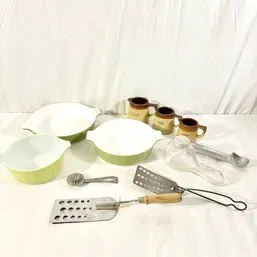 Sale Photo Thumbnail #100: Collection of vintage kitchenware including green Pyrex casserole dishes, small ceramic pitchers, metal spatulas, and glass kitchen utensils.