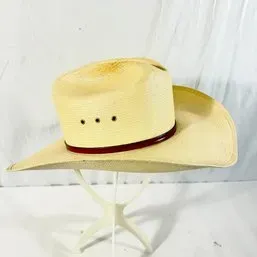 Sale Photo Thumbnail #244: Natural woven straw cowboy hat featuring a reddish-brown hatband and side eyelets for ventilation.