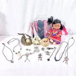 Sale Photo Thumbnail #169: Collection of Native American-style souvenir items including a doll in traditional dress, dreamcatcher and corded necklaces, small figurines, and a woven basket.