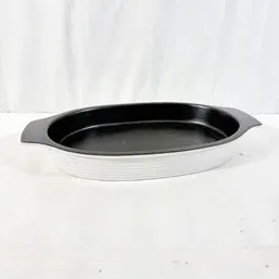 Sale Photo Thumbnail #210: Vintage oval ceramic casserole dish with a ribbed white exterior and black interior.