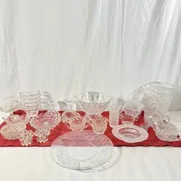 Sale Photo Thumbnail #102: Collection of vintage pressed and cut clear glass tableware including serving bowls, plates, creamers, and decorative dishes displayed on a red runner.
