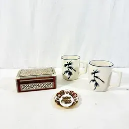 Sale Photo Thumbnail #80: Inlaid wooden trinket box paired with a small crest dish and a set of two ceramic mugs featuring pine tree graphics.