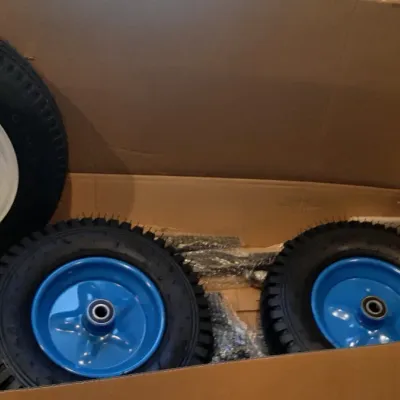 Set of utility and trailer wheels, including a white steel rim trailer tire and two blue metal hub pneumatic wheels inside a cardboard box.
