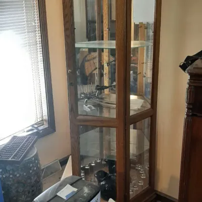 Tall wooden curio cabinet featuring glass display shelves, a mirrored back, and interior lighting.