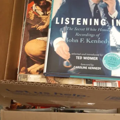 Cardboard box filled with assorted books, featuring 'Listening In: The Secret White House Recordings of John F. Kennedy' by Ted...