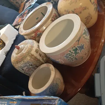 Collection of Asian-style ceramic planters, ginger jars, and decorative urns featuring floral and figurative motifs.