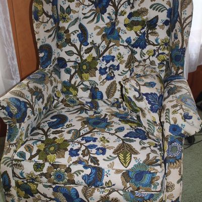 Sale Photo Thumbnail #66: Vintage high-back wingback armchair featuring a vibrant blue, green, and brown floral jacquard upholstery with tufted back detail and dark stained wooden legs.