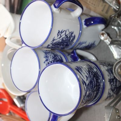 Sale Photo Thumbnail #63: Set of vintage blue and white ceramic mugs featuring sailing ship motifs and dark blue trim, shown stacked alongside various kitchen gadgets.