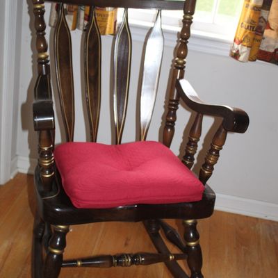 Sale Photo Thumbnail #93: Vintage dark-stained wooden Boston rocker featuring gold-painted stenciled floral details and gold accents, complete with a red tufted seat cushion.