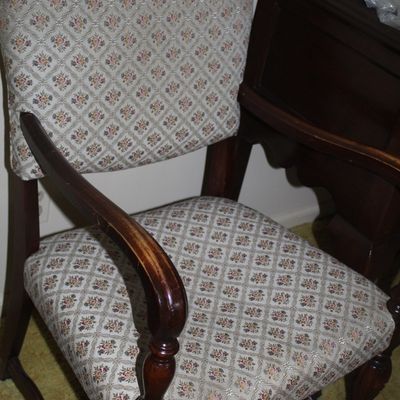 Sale Photo Thumbnail #44: Vintage upholstered armchair with dark wood frame and small floral diamond-pattern fabric, showing light finish wear on the wooden arms.