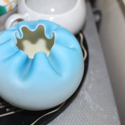 Sale Photo Thumbnail #59: Fenton light blue cased satin glass rose bowl with a crimped, ruffled rim and a white interior.
