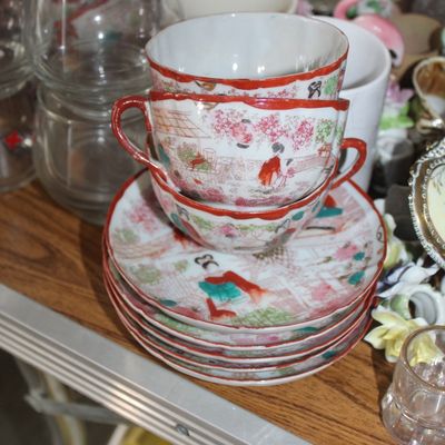 Sale Photo Thumbnail #9: Stack of vintage Japanese eggshell porcelain teacups and saucers featuring hand-painted geisha scenes with red trim.