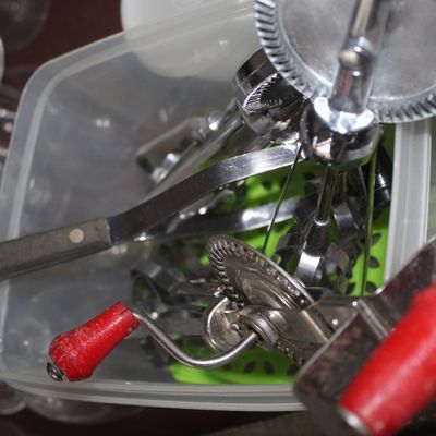 Sale Photo Thumbnail #60: Collection of vintage stainless steel hand-crank eggbeaters and kitchen utensils stored in a plastic tub.