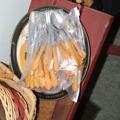 Sale Photo Thumbnail #3: Clear plastic bag of vintage flatware with faux-horn or wood-style handles, resting on a round commemorative decorative tray.