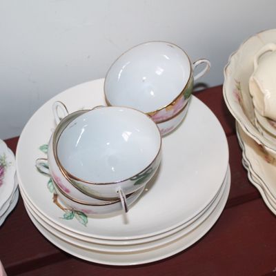 Sale Photo Thumbnail #16: Collection of vintage floral porcelain tableware, including dual-handled teacups, saucers, and serving plates with gold trim.