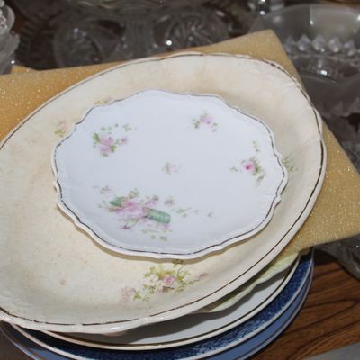 Sale Photo Thumbnail #5: Stack of antique floral porcelain plates and platters with gilded rims, accompanied by surrounding glassware.