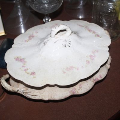 Sale Photo Thumbnail #36: Antique porcelain covered vegetable tureen with delicate pink floral transferware patterns and molded handles, displayed alongside a brass carriage clock and glassware.