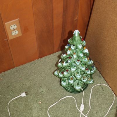 Sale Photo Thumbnail #71: Vintage illuminated ceramic Christmas tree with snow-tipped branches and colorful plastic bulbs, resting on green shag carpet.