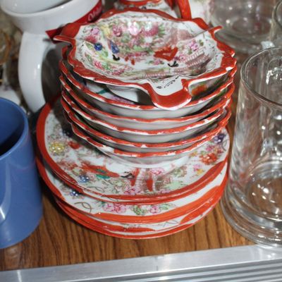 Sale Photo Thumbnail #10: Stack of vintage Japanese Kutani hand-painted porcelain saucers and leaf-shaped dishes with red trim and floral landscapes.
