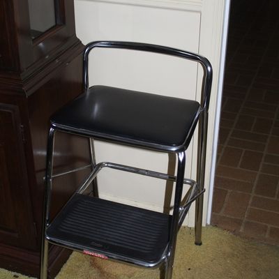 Sale Photo Thumbnail #43: Vintage Cosco chrome step stool chair featuring a black vinyl padded seat and a pull-out step ladder.