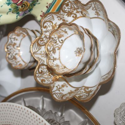 Sale Photo Thumbnail #29: Stacked set of vintage white porcelain bowls featuring scalloped edges and ornate gold gilt scrollwork detailing.