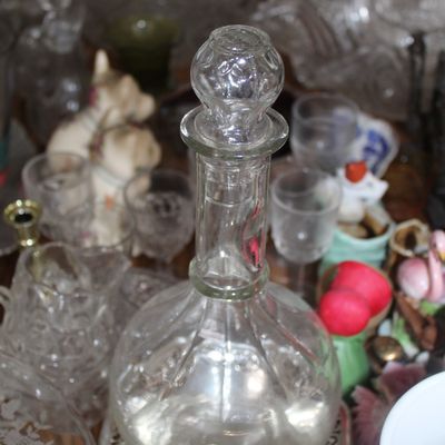 Sale Photo Thumbnail #12: Vintage clear glass decanter with a faceted glass stopper, surrounded by various glassware and collectibles.
