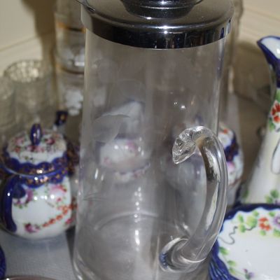 Sale Photo Thumbnail #51: Vintage glass cocktail pitcher featuring etched floral designs and a chrome-plated lid with a built-in strainer spout.