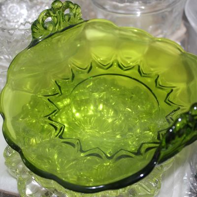 Sale Photo Thumbnail #26: Vintage green glass nappy dish featuring decorative openwork handles and a ruffled, starburst-patterned rim.