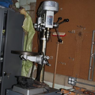Sale Photo Thumbnail #100: Vintage floor-standing drill press mounted on a grey metal cabinet base in a workshop setting.