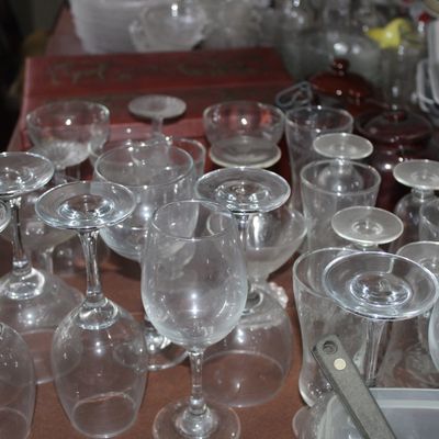 Sale Photo Thumbnail #61: Large collection of assorted clear glassware, including stemmed wine glasses, goblets, and tumblers arranged on a table.